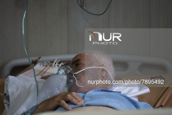 An Iranian elderly man who is infected by COVID-19 uses oxygen as he lies on a hospital bed at a COVID-19 ward in a hospital in the holy cit...