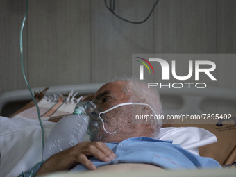 An Iranian elderly man who is infected by COVID-19 uses oxygen as he lies on a hospital bed at a COVID-19 ward in a hospital in the holy cit...