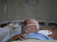 An Iranian elderly man who is infected by COVID-19 uses oxygen as he lies on a hospital bed at a COVID-19 ward in a hospital in the holy cit...