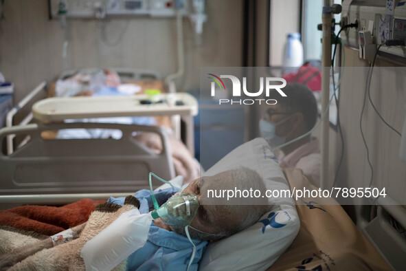 An Iranian elderly man who is infected by COVID-19 uses oxygen as he lies on a hospital bed at a COVID-19 ward in a hospital in the holy cit...