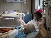 An Iranian elderly man who is infected by COVID-19 uses oxygen as he lies on a hospital bed at a COVID-19 ward in a hospital in the holy cit...