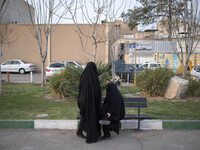 Two veiled women on a street-side in the holy city of Qom 145Km (90 miles) south of Tehran on March 10, 2022. (