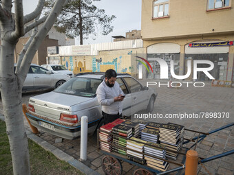 A cleric uses his smartphone while standing next to a cart loaded with religious books on a street-side in the holy city of Qom 145Km (90 mi...