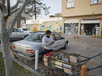 A cleric uses his smartphone while standing next to a cart loaded with religious books on a street-side in the holy city of Qom 145Km (90 mi...