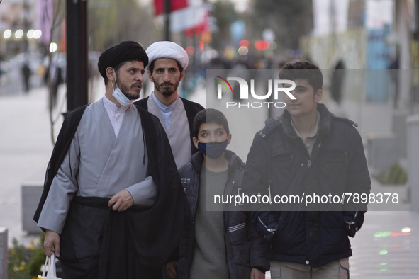 Two clerics and youths walk along a street in the holy city of Qom 145Km (90 miles) south of Tehran on March 10, 2022. 