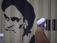 An Iranian cleric walks past a graffiti of Ayatollah Ruhollah Khomeini, founder and first spiritual leader of the Islamic Republic of Iran,...