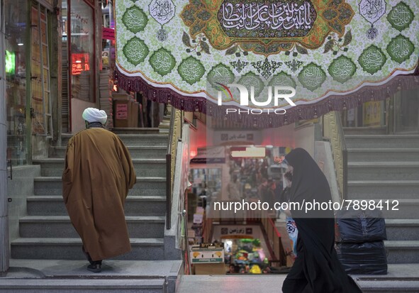 An Iranian veiled woman walks past a religious shopping center in the holy city of Qom 145Km (90 miles) south of Tehran on March 10, 2022. 