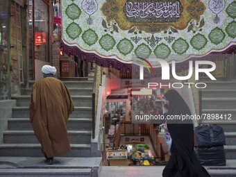 An Iranian veiled woman walks past a religious shopping center in the holy city of Qom 145Km (90 miles) south of Tehran on March 10, 2022. (