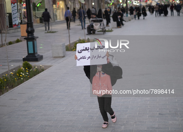 An Iranian young girl demonstrates a placard with a Persian script that said, Hijab means I do not need any look, while walking along a stre...