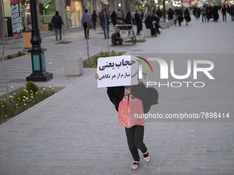 An Iranian young girl demonstrates a placard with a Persian script that said, Hijab means I do not need any look, while walking along a stre...