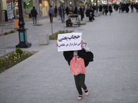 An Iranian young girl demonstrates a placard with a Persian script that said, Hijab means I do not need any look, while walking along a stre...