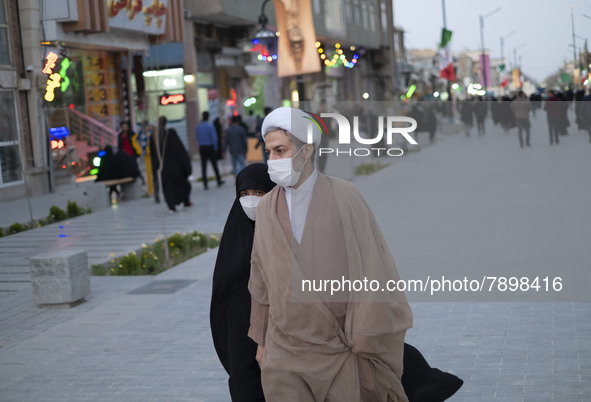 An Iranian cleric and his veiled young daughter wearing protective face masks walk along a street near a shrine in the holy city of Qom 145K...