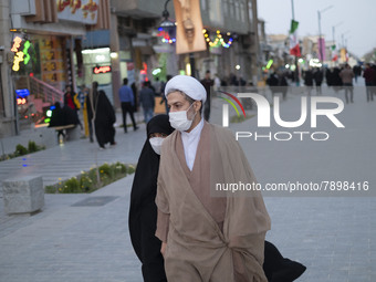 An Iranian cleric and his veiled young daughter wearing protective face masks walk along a street near a shrine in the holy city of Qom 145K...