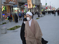 An Iranian cleric and his veiled young daughter wearing protective face masks walk along a street near a shrine in the holy city of Qom 145K...