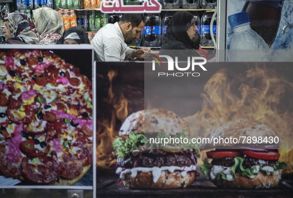 A man and women sit at a small fast-food restaurant near a shrine in the holy city of Qom 145Km (90 miles) south of Tehran on March 10, 2022...