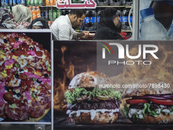 A man and women sit at a small fast-food restaurant near a shrine in the holy city of Qom 145Km (90 miles) south of Tehran on March 10, 2022...