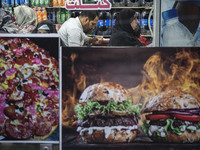 A man and women sit at a small fast-food restaurant near a shrine in the holy city of Qom 145Km (90 miles) south of Tehran on March 10, 2022...