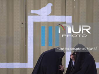 Two Iranian veiled women sit on a street-side near a holy shrine in the holy city of Qom 145Km (90 miles) south of Tehran on March 10, 2022....