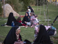 Iranian women sit on a street-side in the holy city of Qom 145Km (90 miles) south of Tehran on March 10, 2022. (