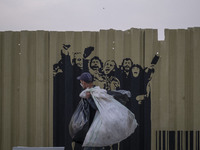 A poor man carrying plastic bags while walking past graffiti on a fence near a holy shrine in the holy city of Qom 145Km (90 miles) south of...