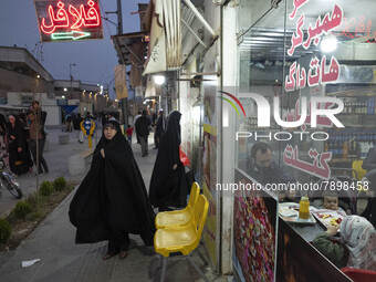 A family sit at a small fast-food restaurant near a holy shrine in the holy city of Qom 145Km (90 miles) south of Tehran on March 10, 2022....