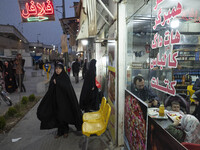 A family sit at a small fast-food restaurant near a holy shrine in the holy city of Qom 145Km (90 miles) south of Tehran on March 10, 2022....