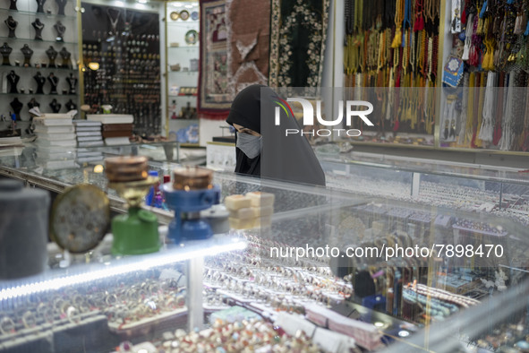 A veiled woman wearing a protective face mask stands at a jewelry shop near a holy shrine in the holy city of Qom 145Km (90 miles) south of...