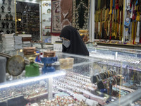 A veiled woman wearing a protective face mask stands at a jewelry shop near a holy shrine in the holy city of Qom 145Km (90 miles) south of...