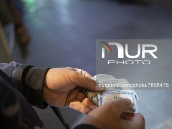 An Iranian street money changer counts U.S. Dollar banknotes while standing on a street-side out of a bazaar (Market) near a holy shrine in...