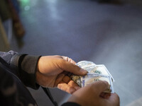 An Iranian street money changer counts U.S. Dollar banknotes while standing on a street-side out of a bazaar (Market) near a holy shrine in...