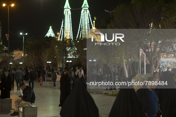 People walk along a pedestrian street near a holy shrine in the holy city of Qom 145Km (90 miles) south of Tehran at night on March 10, 2022...