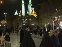 People walk along a pedestrian street near a holy shrine in the holy city of Qom 145Km (90 miles) south of Tehran at night on March 10, 2022...