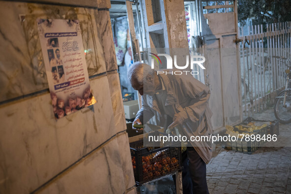 An Iranian elderly man collects cucumber while shopping in the holy city of Qom 145Km (90 miles) south of Tehran at night on March 10, 2022....