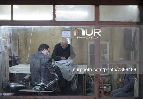 Iranian men sit at an old sewing shop in the holy city of Qom 145Km (90 miles) south of Tehran at night on March 10, 2022. 