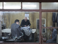 Iranian men sit at an old sewing shop in the holy city of Qom 145Km (90 miles) south of Tehran at night on March 10, 2022. (