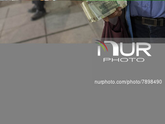 An Iranian street money changer holds Iranian Rial banknotes while standing on a street-side out of a bazaar (Market) near a holy shrine in...