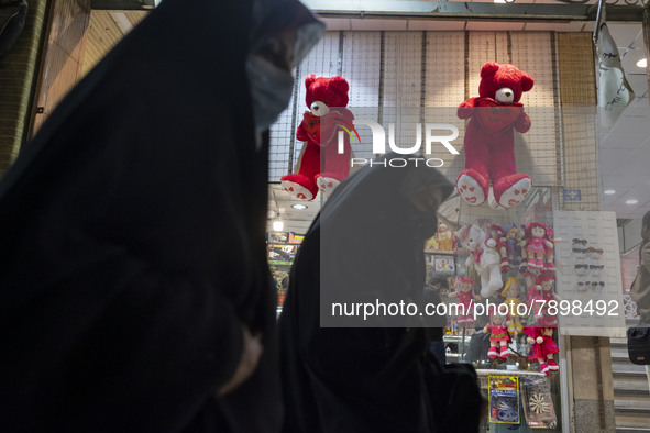 Iranian veiled women walk past two red teddy bears hanged on a wall just out of a toy shop near a holy shrine in the holy city of Qom 145Km...