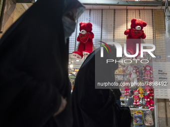 Iranian veiled women walk past two red teddy bears hanged on a wall just out of a toy shop near a holy shrine in the holy city of Qom 145Km...