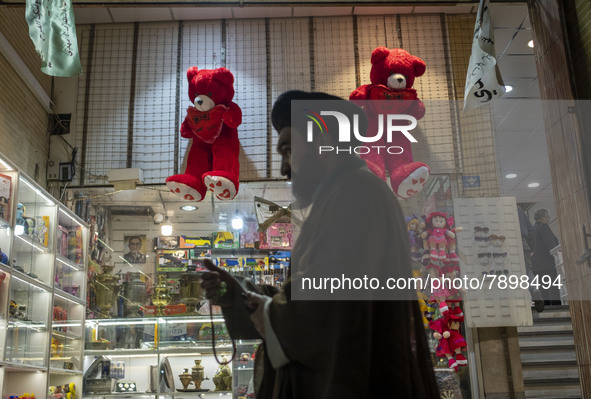 An Iranian cleric walks past two red teddy bears hanged on a wall just out of a toy shop near a holy shrine in the holy city of Qom 145Km (9...