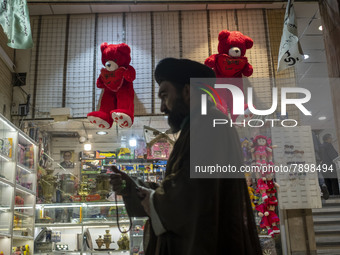 An Iranian cleric walks past two red teddy bears hanged on a wall just out of a toy shop near a holy shrine in the holy city of Qom 145Km (9...