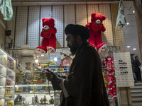 An Iranian cleric walks past two red teddy bears hanged on a wall just out of a toy shop near a holy shrine in the holy city of Qom 145Km (9...