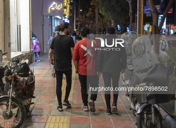 Iranian youths walk along a street-side in the holy city of Qom 145Km (90 miles) south of Tehran on March 10, 2022. 