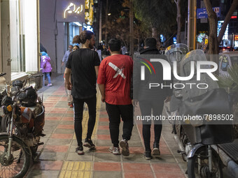 Iranian youths walk along a street-side in the holy city of Qom 145Km (90 miles) south of Tehran on March 10, 2022. (