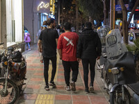 Iranian youths walk along a street-side in the holy city of Qom 145Km (90 miles) south of Tehran on March 10, 2022. (