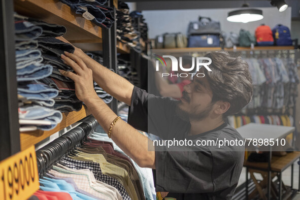 An Iranian salesman adjusts jeans at a shelf in a dress shop in the holy city of Qom145Km (90 miles) south of Tehran on March 10, 2022. 