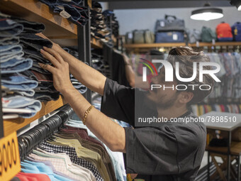 An Iranian salesman adjusts jeans at a shelf in a dress shop in the holy city of Qom145Km (90 miles) south of Tehran on March 10, 2022. (