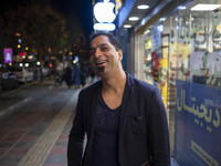 An Iranian man smiles as he poses for a photograph on a street-side in the holy city of Qom 145Km (90 miles) south of Tehran on March 10, 20...