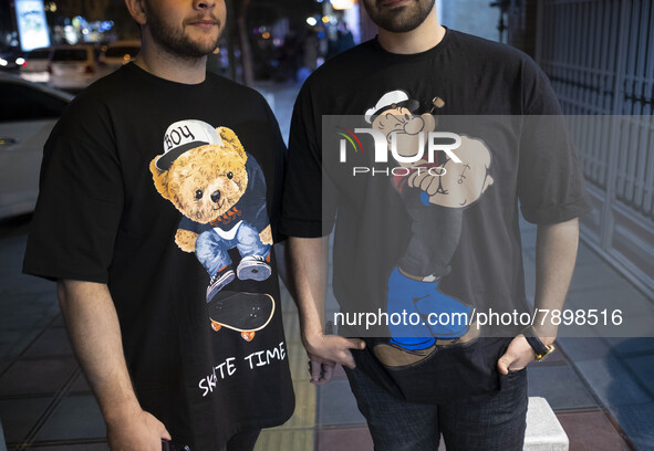 Two Iranian men pose for a photograph on a street-side in the holy city of Qom 145Km (90 miles) south of Tehran on March 10, 2022. 