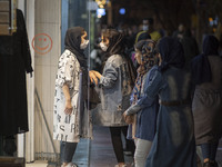 Iranian youths speak with each other while standing in front of a dress shop window in the holy city of Qom 145Km (90 miles) south of Tehran...