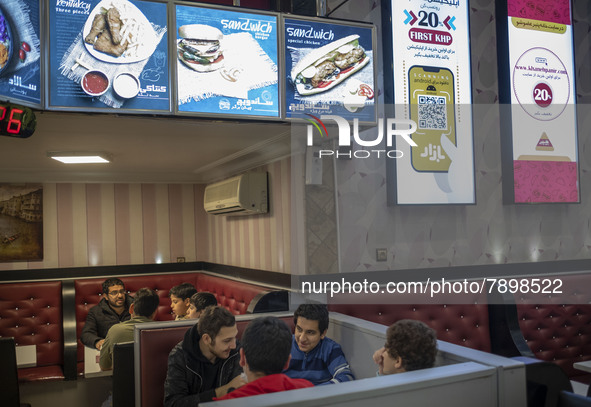 Iranian youths sit in a fast-food restaurant in the holy city of Qom 145Km (90 miles) south of Tehran on March 10, 2022. 